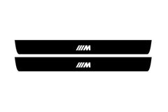 Catalog illustration of two black front door sill plates with ///M lettering.
