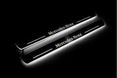 Two long door sill plates with Mercedes-Benz lettering and edges illuminated in white, angled view on a dark background.