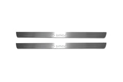 Two long silver-finished door sill plates with smart with circular arrow emblems lettering on a light background, straight-on view.
