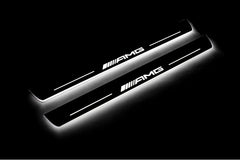 Two long door sill plates with AMG lettering and edges illuminated in white, angled view on a dark background.