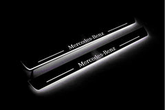 Two long door sill plates with Mercedes-Benz lettering and edges illuminated in white, angled view on a dark background.