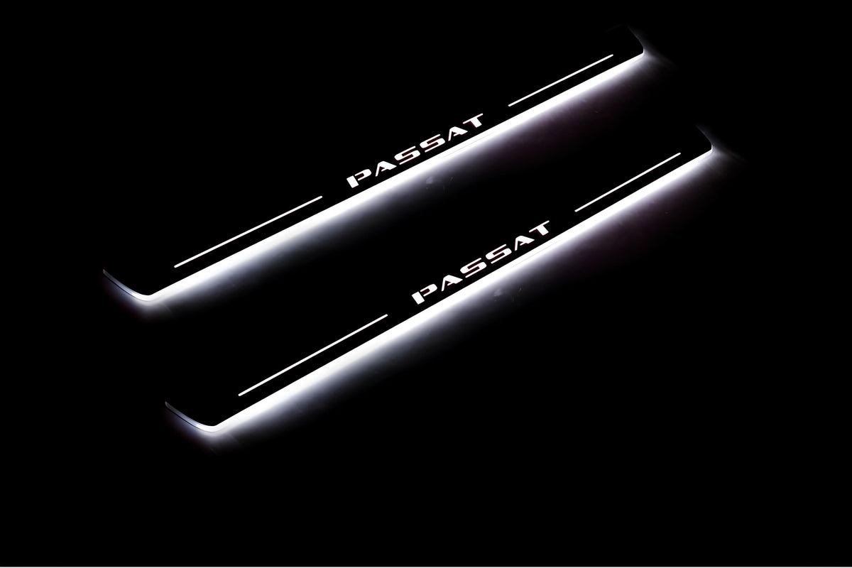 Two long door sill plates with Passat lettering and edges illuminated in white, angled view on a dark background.