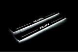 Two long door sill plates with Acura lettering and edges illuminated in white, angled view on a dark background.