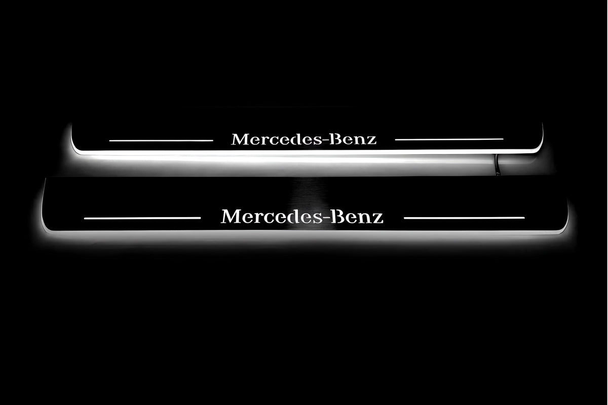 Two long door sill plates with Mercedes-Benz lettering and edges illuminated in white, straight-on view on a dark background.