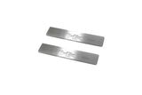 Two short silver-finished door sill plates with H2 lettering on a light background, angled view.