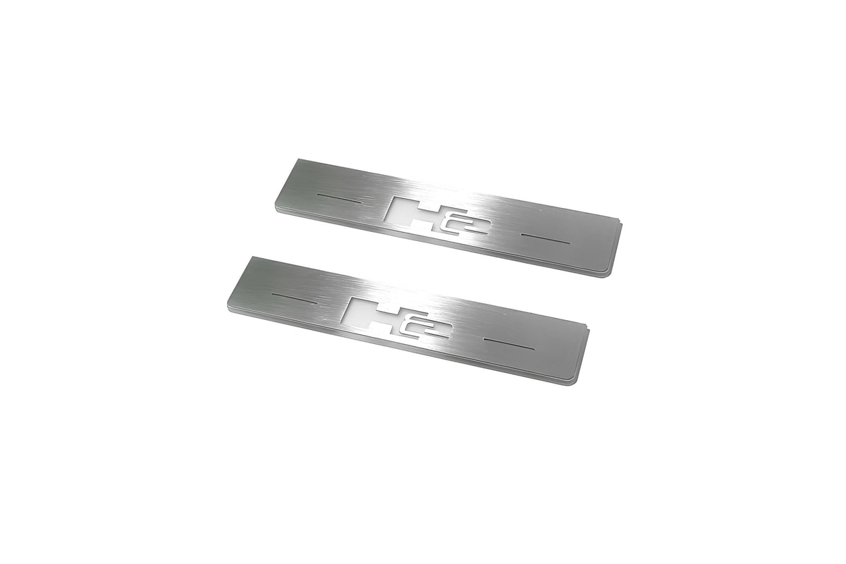 Two short silver-finished door sill plates with H2 lettering on a light background, angled view.