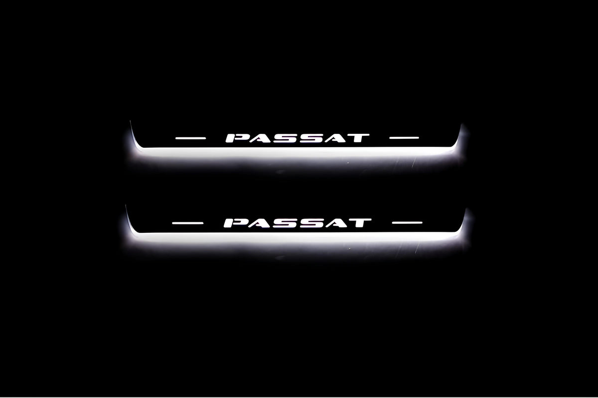 Two short door sill plates with Passat lettering and edges illuminated in white, straight-on view on a dark background.