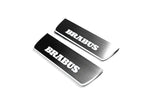Two short silver-finished door sill plates with Brabus lettering on a light background, angled view.