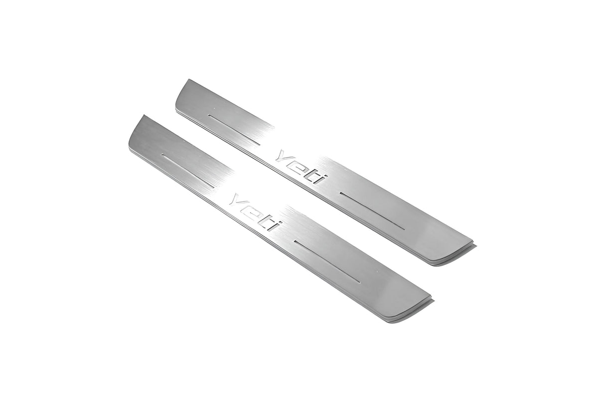 Two long silver-finished door sill plates with Yeti lettering on a light background, angled view.