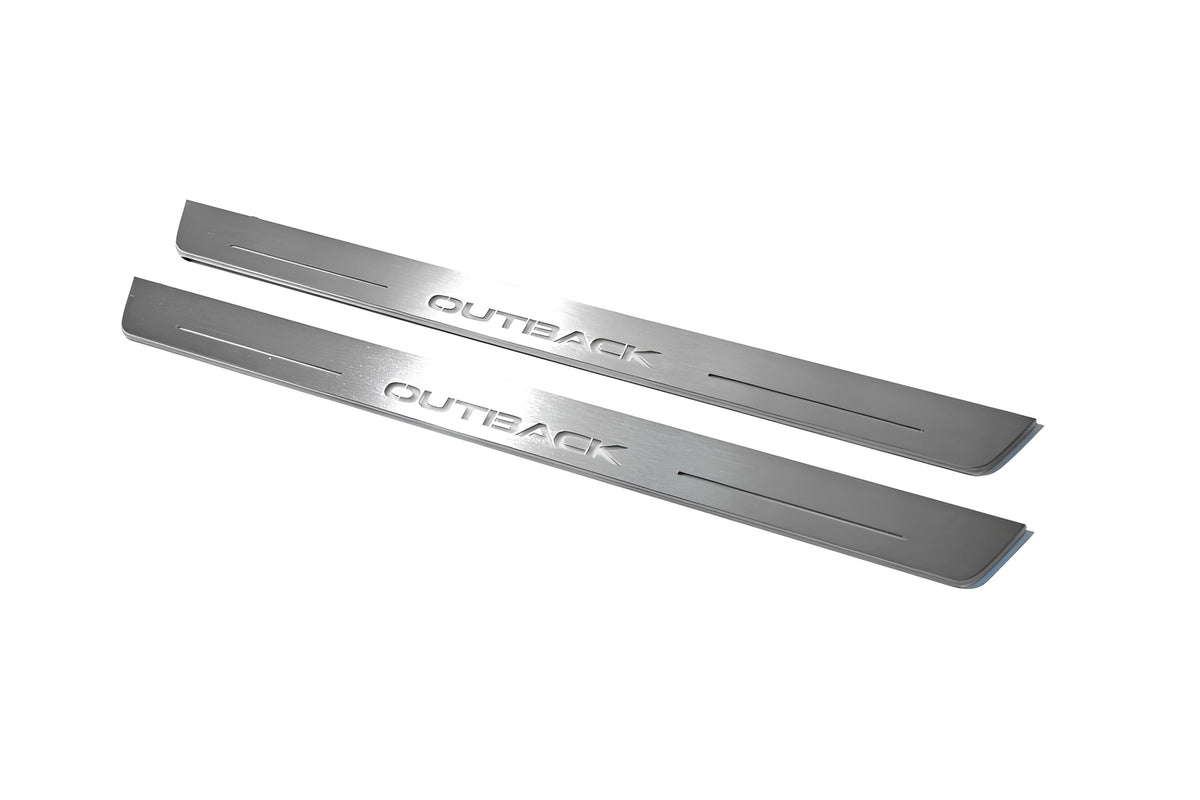 Two long silver-finished door sill plates with Outback lettering on a light background, angled view.