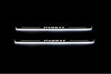 Two long door sill plates with Passat lettering and edges illuminated in white, straight-on view on a dark background.