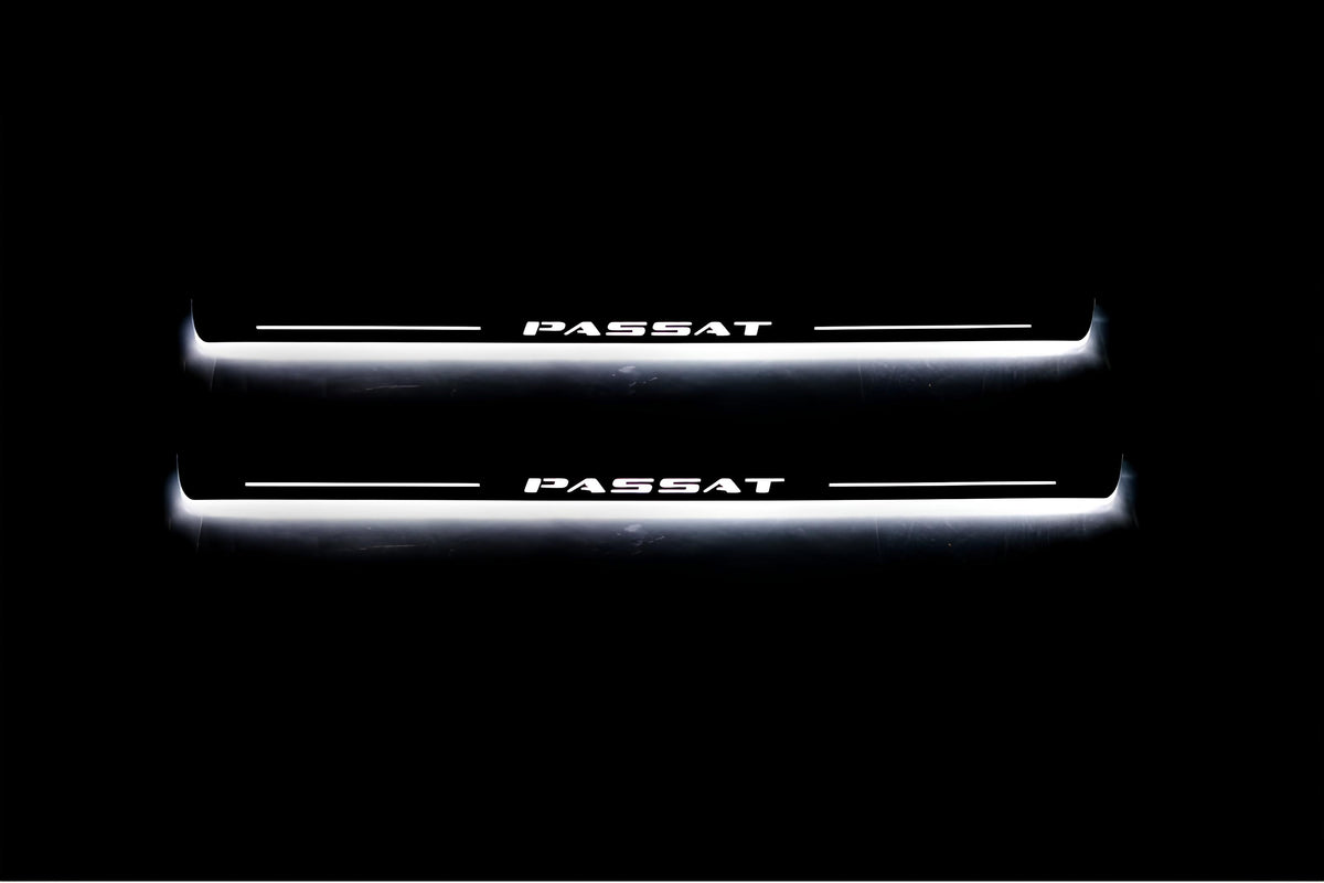 Two long door sill plates with Passat lettering and edges illuminated in white, straight-on view on a dark background.