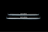 Two long door sill plates with Acura lettering and edges illuminated in white, straight-on view on a dark background.