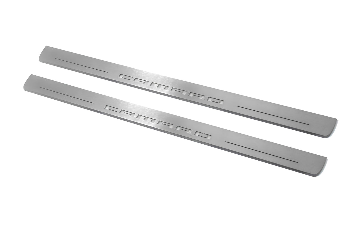 Two long silver-finished door sill plates with Camaro lettering on a light background, angled view.