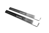 Two long reflective dark door sill plates with white Acura lettering and horizontal lines on a white background, angled view.