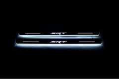 Two long door sill plates with SRT lettering and edges illuminated in white, straight-on view on a dark background.