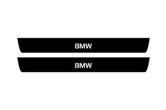 Catalog illustration of two black front door sill plates with BMW lettering.