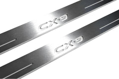 Close-up of CX-9 lettering and linear slots in silver-finished door sill plates.