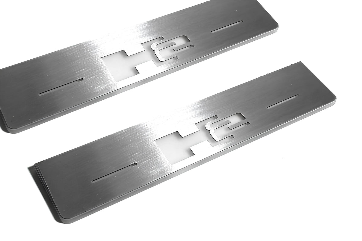 Close-up of H2 lettering and linear slots in silver-finished door sill plates.