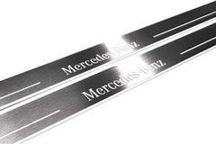 Close-up of Mercedes-Benz lettering and linear slots in silver-finished door sill plates.