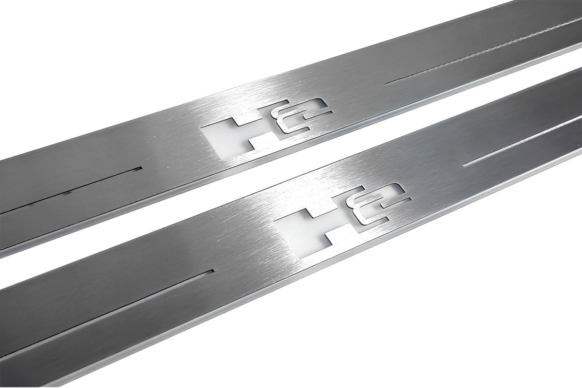 Close-up of H2 lettering and linear slots in silver-finished door sill plates.