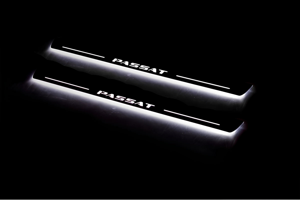 Two long door sill plates with Passat lettering and edges illuminated in white, angled view on a dark background.
