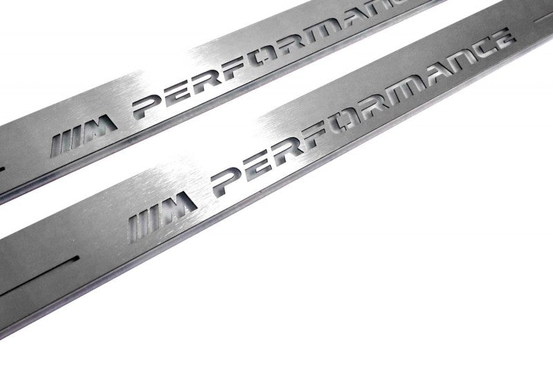Close-up of M Performance lettering and linear slots in silver-finished door sill plates.