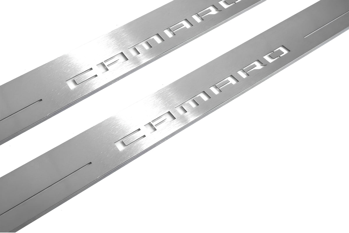 Close-up of Camaro lettering and linear slots in silver-finished door sill plates.