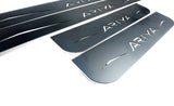 Close-up of four reflective dark-finished Ariya door sill plates and their angular graphics.