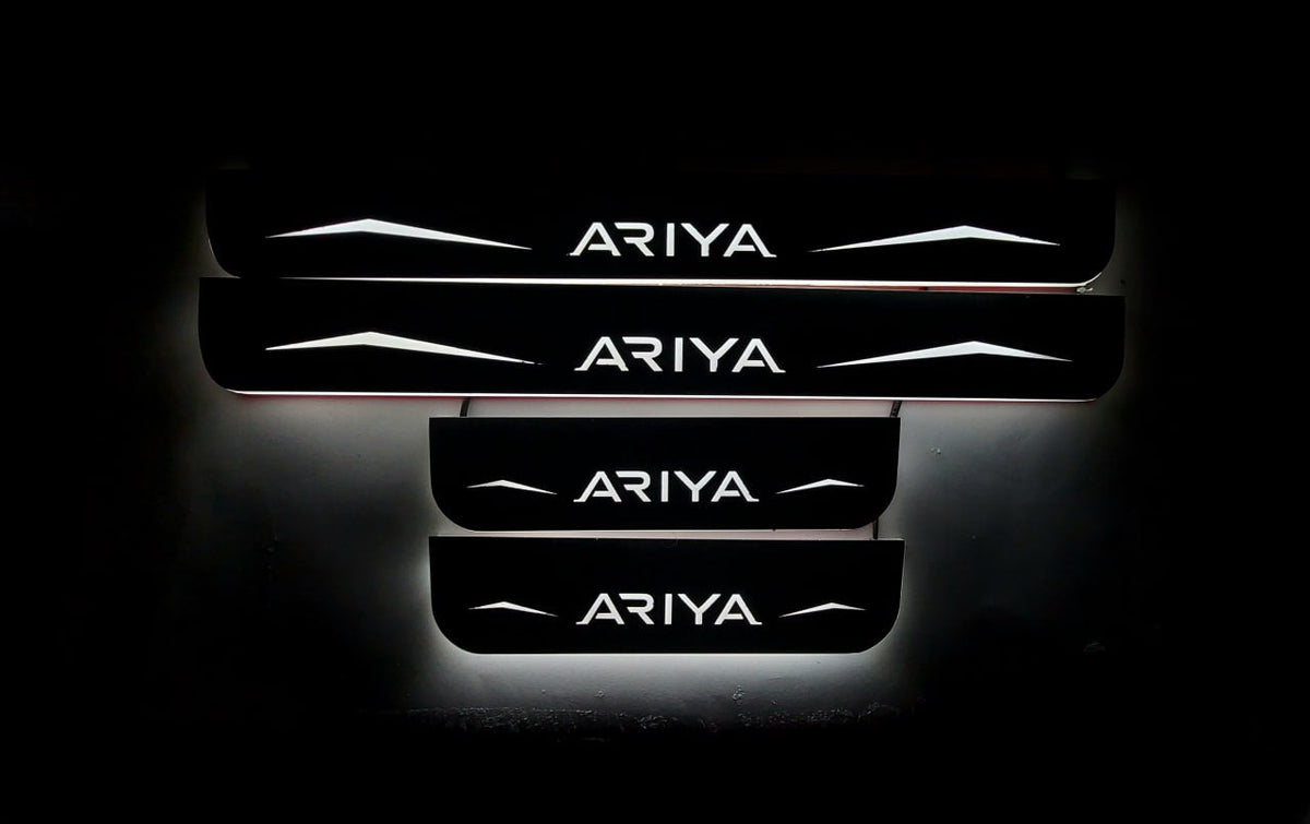 Four dark door sill plates with Ariya lettering, angular graphics and illuminated edges on a black background, straight-on view.