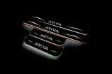 Four dark door sill plates with Ariya lettering, angular graphics and illuminated edges on a black background, angled view.