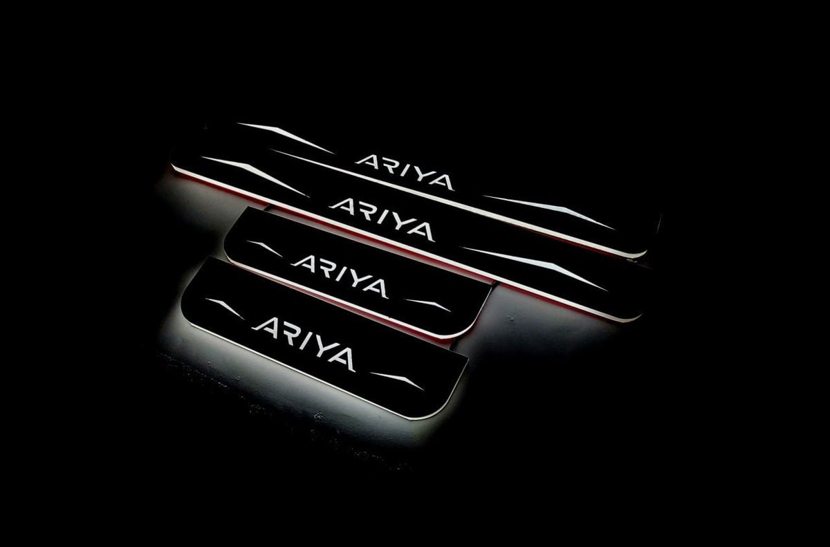 Four dark door sill plates with Ariya lettering, angular graphics and illuminated edges on a black background, angled view.