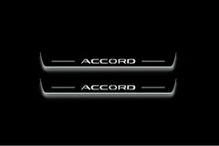 Two long door sill plates with Accord lettering and edges illuminated in white, straight-on view on a dark background.