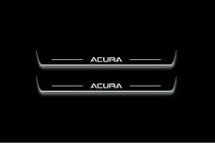 Two long door sill plates with Acura lettering and edges illuminated in white, straight-on view on a dark background.