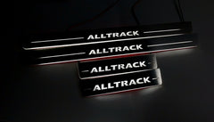 Four dark door sill plates with white Alltrack lettering and illuminated edges, angled view on a dark surface.