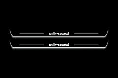 Two long door sill plates with allroad lettering and edges illuminated in white, straight-on view on a dark background.