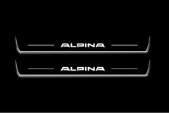 Two long door sill plates with Alpina lettering and edges illuminated in white, straight-on view on a dark background.