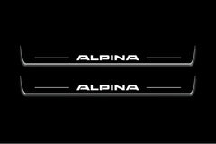 Two long door sill plates with Alpina lettering and edges illuminated in white, straight-on view on a dark background.