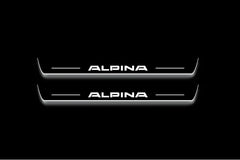 Two long door sill plates with Alpina lettering and edges illuminated in white, straight-on view on a dark background.
