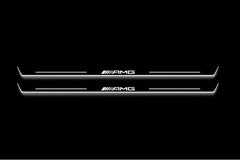 Two long door sill plates with AMG lettering and edges illuminated in white, straight-on view on a dark background.