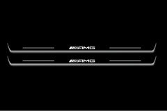 Two long door sill plates with AMG lettering and edges illuminated in white, straight-on view on a dark background.