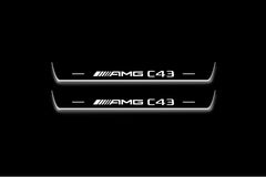 Two long door sill plates with AMG C43 lettering and edges illuminated in white, straight-on view on a dark background.