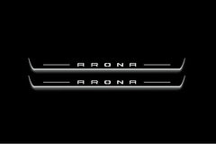 Two long door sill plates with Arona lettering and edges illuminated in white, straight-on view on a dark background.