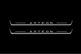 Two long door sill plates with Arteon lettering and edges illuminated in white, straight-on view on a dark background.