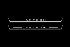 Two long door sill plates with Arteon lettering and edges illuminated in white, straight-on view on a dark background.