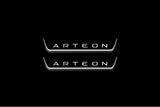 Two short door sill plates with Arteon lettering and edges illuminated in white, straight-on view on a dark background.