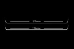 Two long door sill plates with Cadillac in script lettering and edges illuminated in white, straight-on view on a dark background.