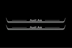 Two long door sill plates with Audi A6 lettering and edges illuminated in white, straight-on view on a dark background.