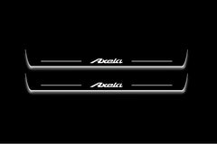 Two long door sill plates with Axela lettering and edges illuminated in white, straight-on view on a dark background.