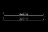 Two long door sill plates with Beetle lettering and edges illuminated in white, straight-on view on a dark background.